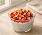 Pudin de chía y yogur en un vaso con fresas troceadas y almendras laminadas tostadas
